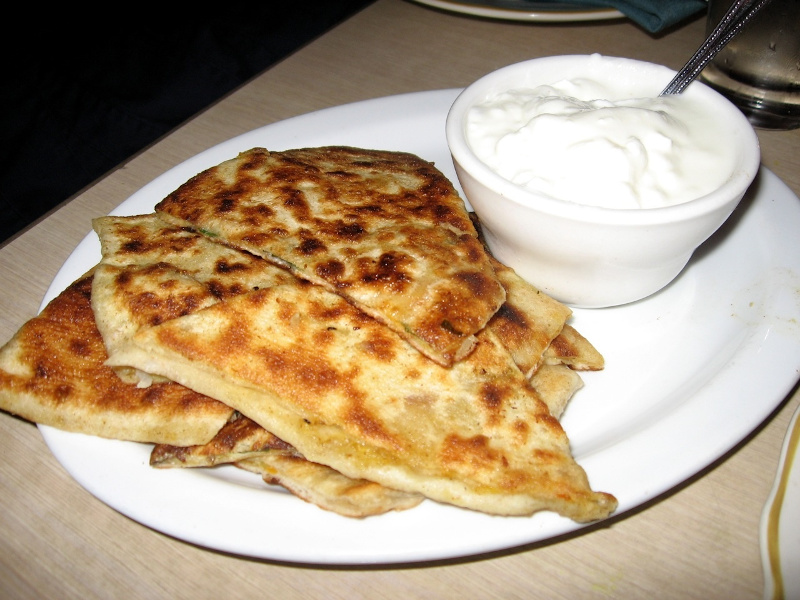 A plate of bolani with a side of yogurt
