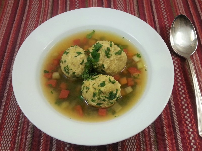 A bowl of chicken broth with gundi dumplings