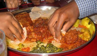 Diners eating from a platter of Ethiopian dishes